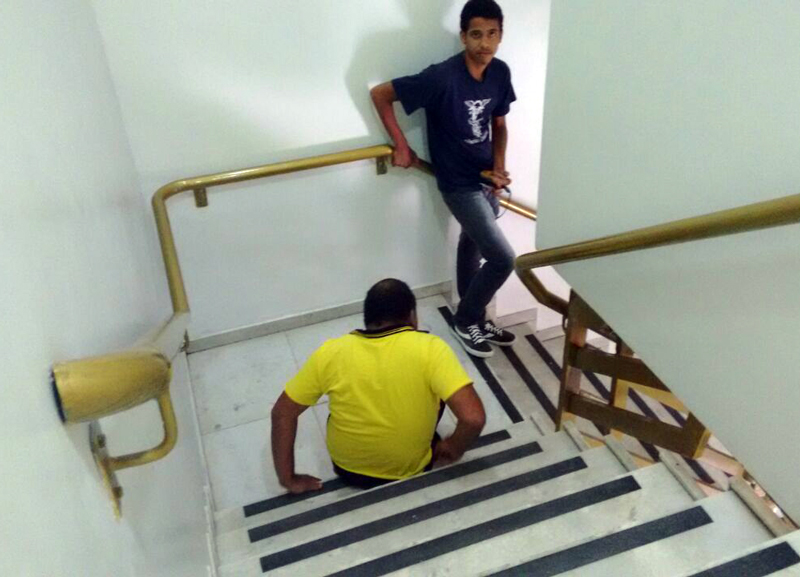 Deficiente físico desce as escadas da agência se arrastando por causa da falta de elevador na agência